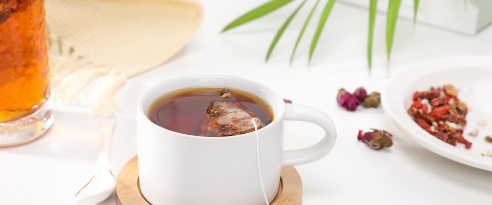 Non-toxic tea bags and loose leaf tea with a stainless steel infuser on a wooden surface